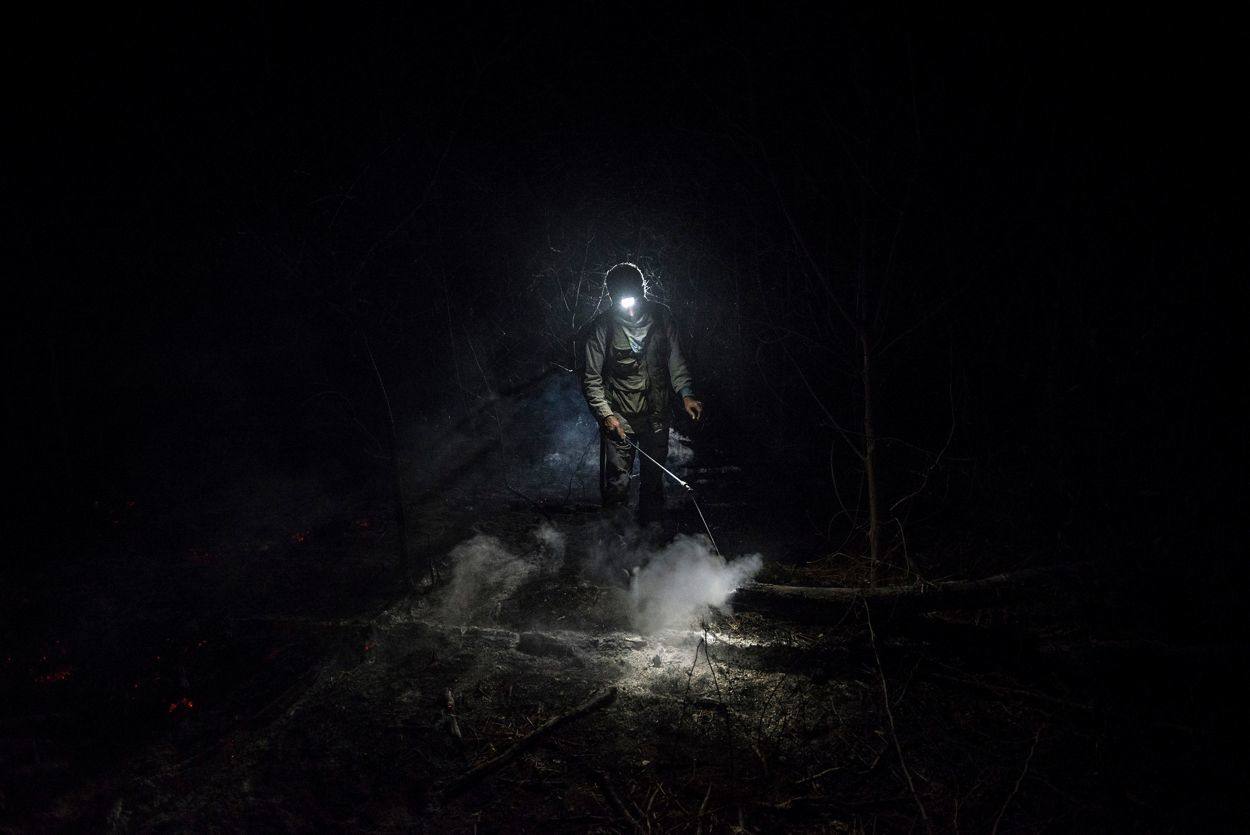 El bombero forestal voluntario Daniel Vargas Osinaga (21) camina a través de un espeso humo en Santa Rosa de Tucabaca, Bolivia