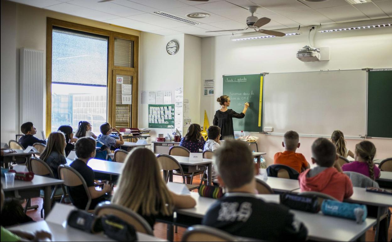 Una profesora impartiendo clase en un aula. 