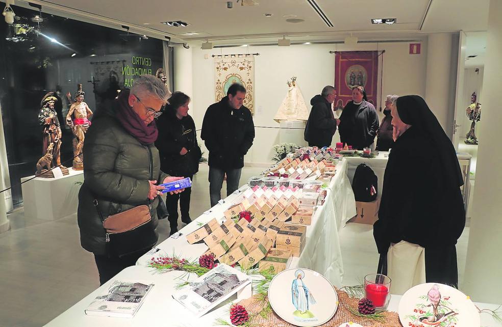 Las hermanas del monasterio de Vico atienden la exposición y venta de sus productos, rodeada por las imágenes de los 24 santos de Arnedo. 