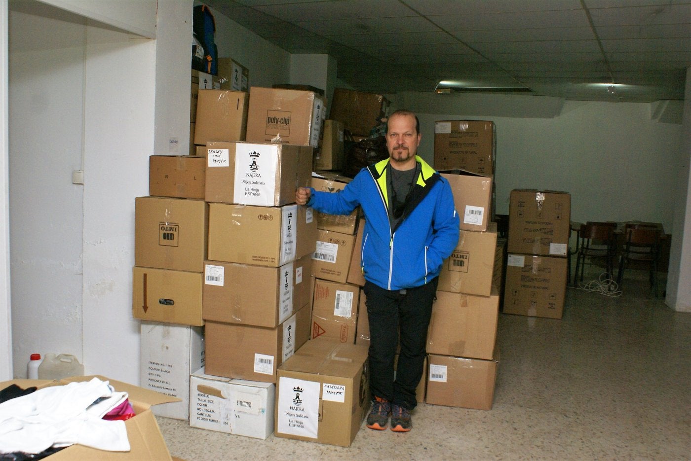 Entrada de la sede de Nájera Solidaria, en la calle Badarán, y Adolfo Fernández junto a diverso material listo para vender. 