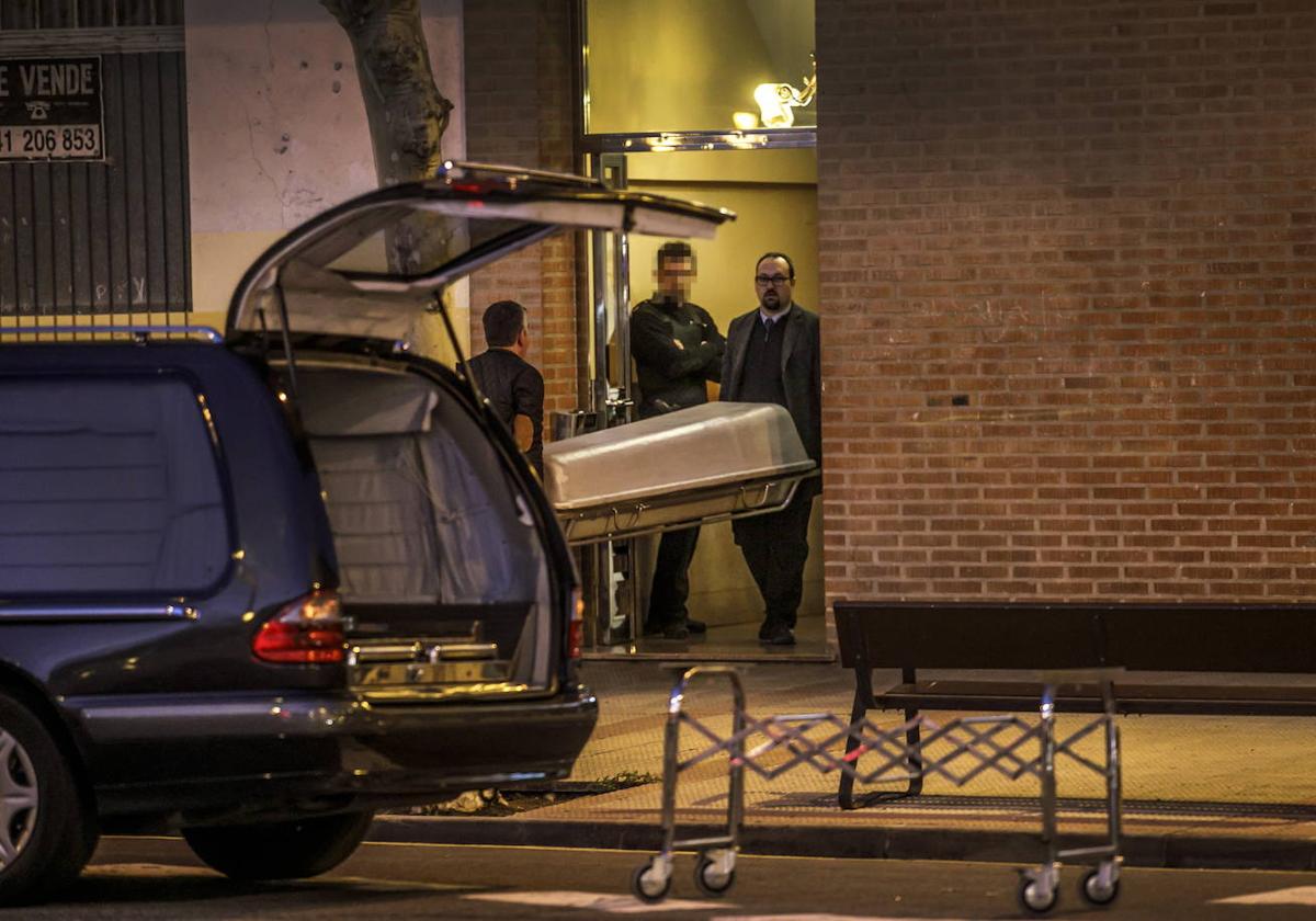 Miembros de la funeraria sacan el cadáver del hombre asesinado en la calle Pepe Blanco.