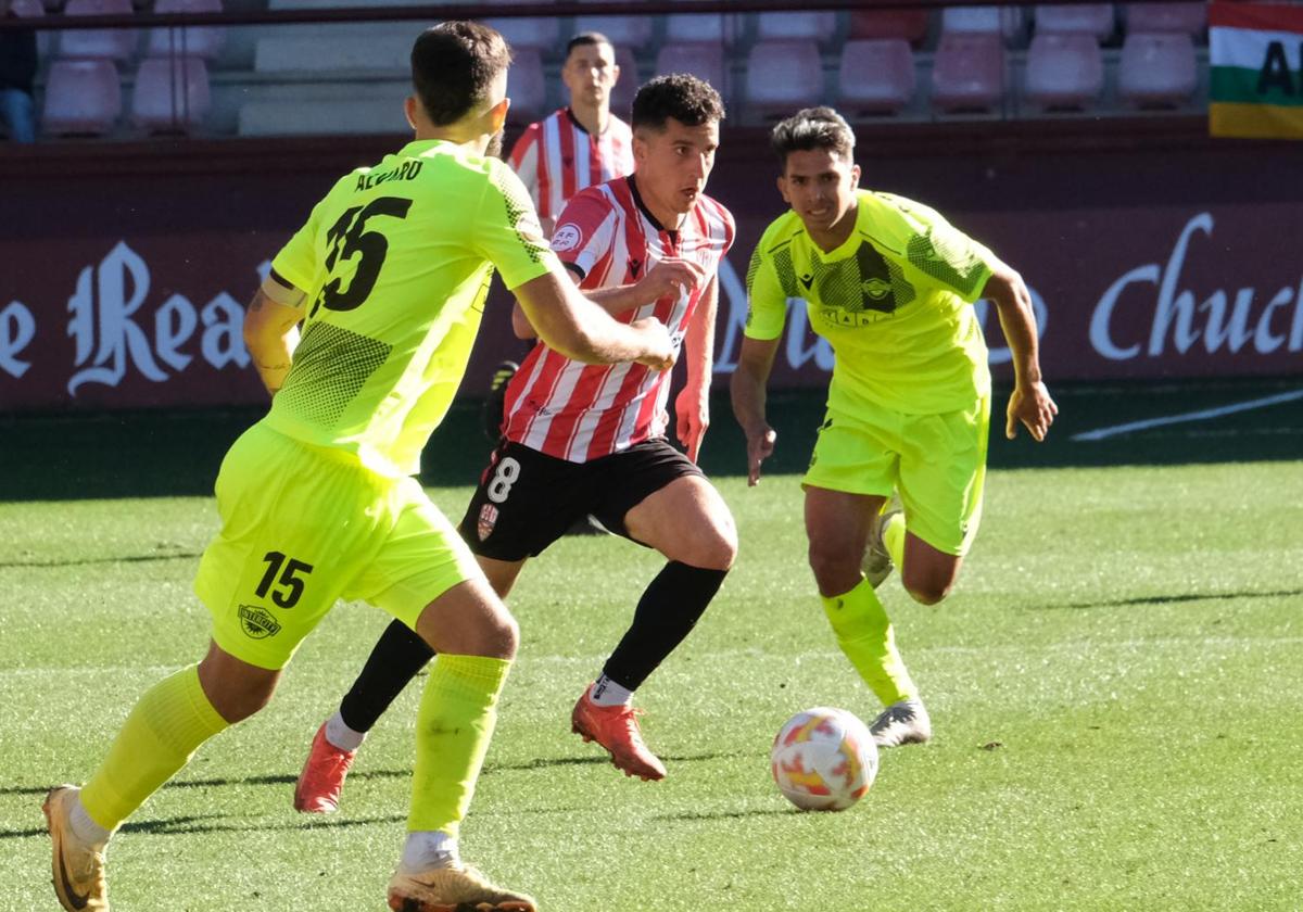 Sierra conduce el balón entre dos rivales.