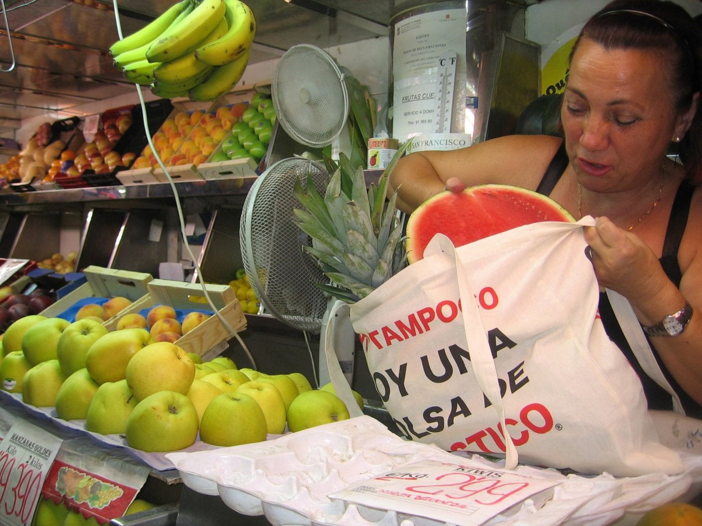 Una frutera utiliza una bolsa de tela para meter la compra.