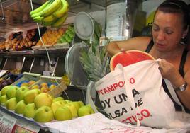 Una frutera utiliza una bolsa de tela para meter la compra.