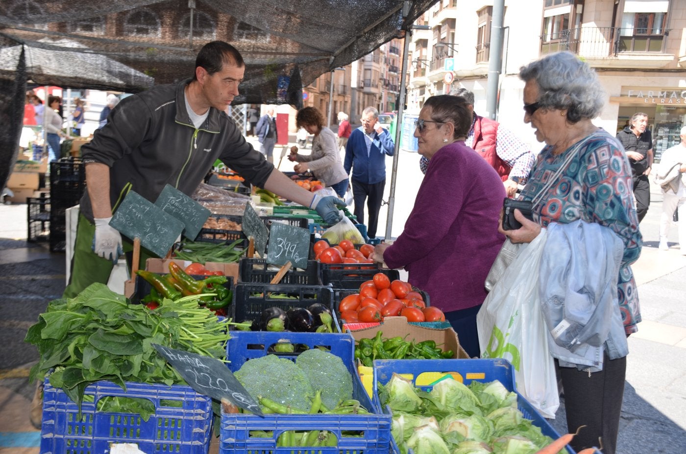 Clientas en un puesto de frutas y hortalizas, comprando ayer en el mercado de la plaza del Raso.