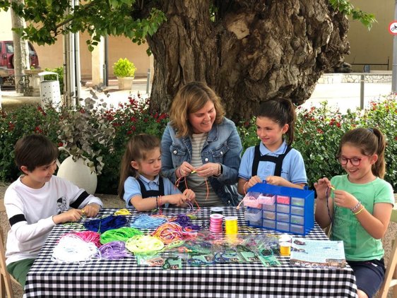 Los niños de Sorzano Mateo, Ana, María y Paula, junto a la catequista Rosa, elaboran pulseras-rosario.