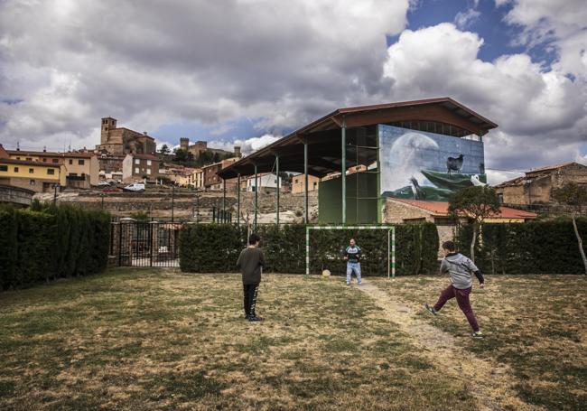 Dioni y Oier juegan a fútbol en el recreo con el maestro Guillermo ejerciendo de portero.