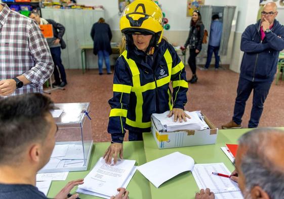 Una trabajadora Correos entrega en la mesa de un colegio electoral los votos por correo.