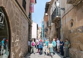 Visitantes junto a la oficina de turismo y el edificio recientemente declarado en ruina, en la calle Mayor.