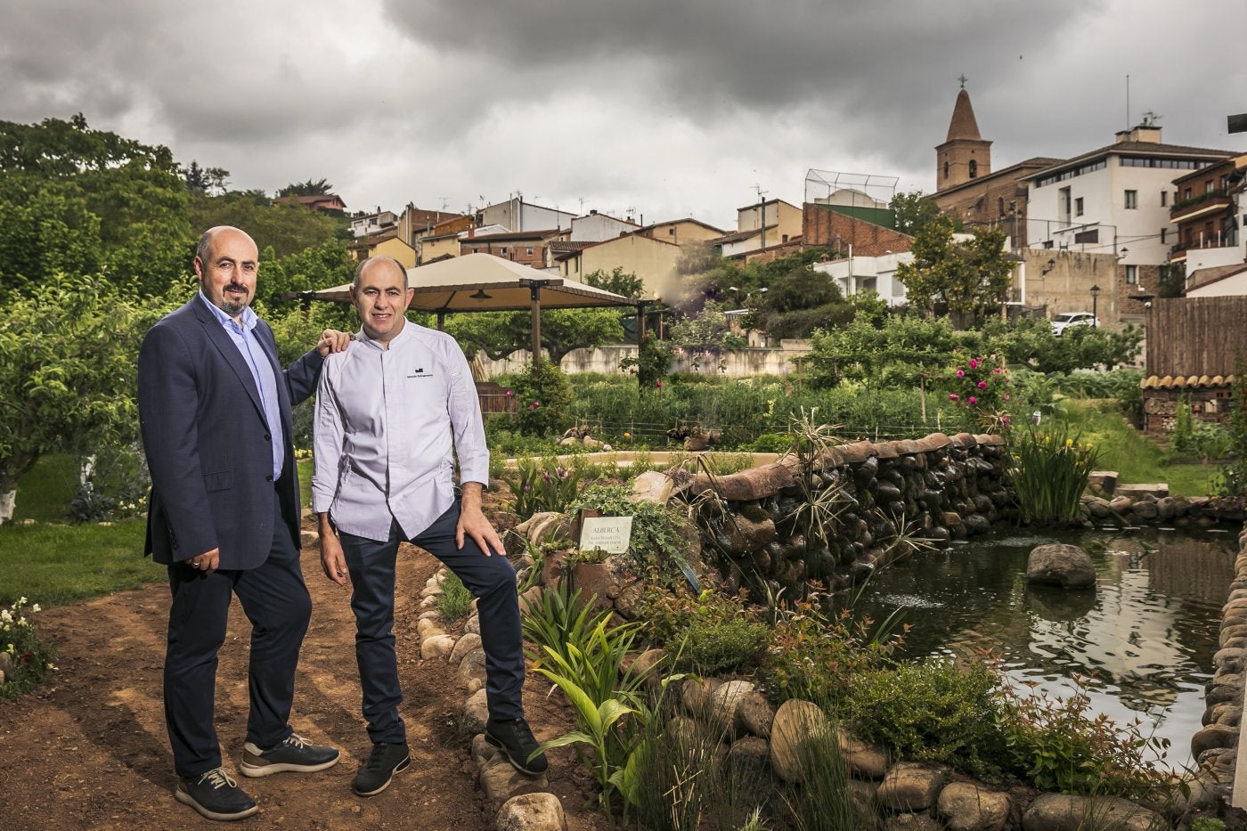 Los hermanos Echapresto junto a la alberca de la huerta donde mineralizan el agua de lluvia antes de usarla para regar.