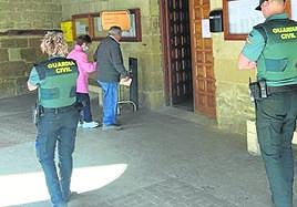 Dos personas acuden a votar al Ayuntamiento de San Asensio este domingo, ante la mirada de dos agentes de la Guardia Civil.