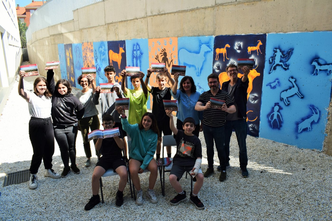 Alumnos y coordinadores del proyecto de innovación educativa posan con el teniente de alcalde en funciones, Enrique San Román, junto al mural 'Proyecto Rupestre' pintado en el centro.