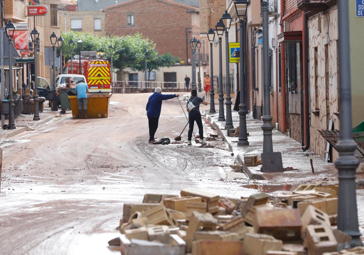 Varios vecinos se afanan en la limpieza de la calle principal de Huércanos.