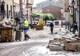 Varios vecinos se afanan en la limpieza de la calle principal de Huércanos.