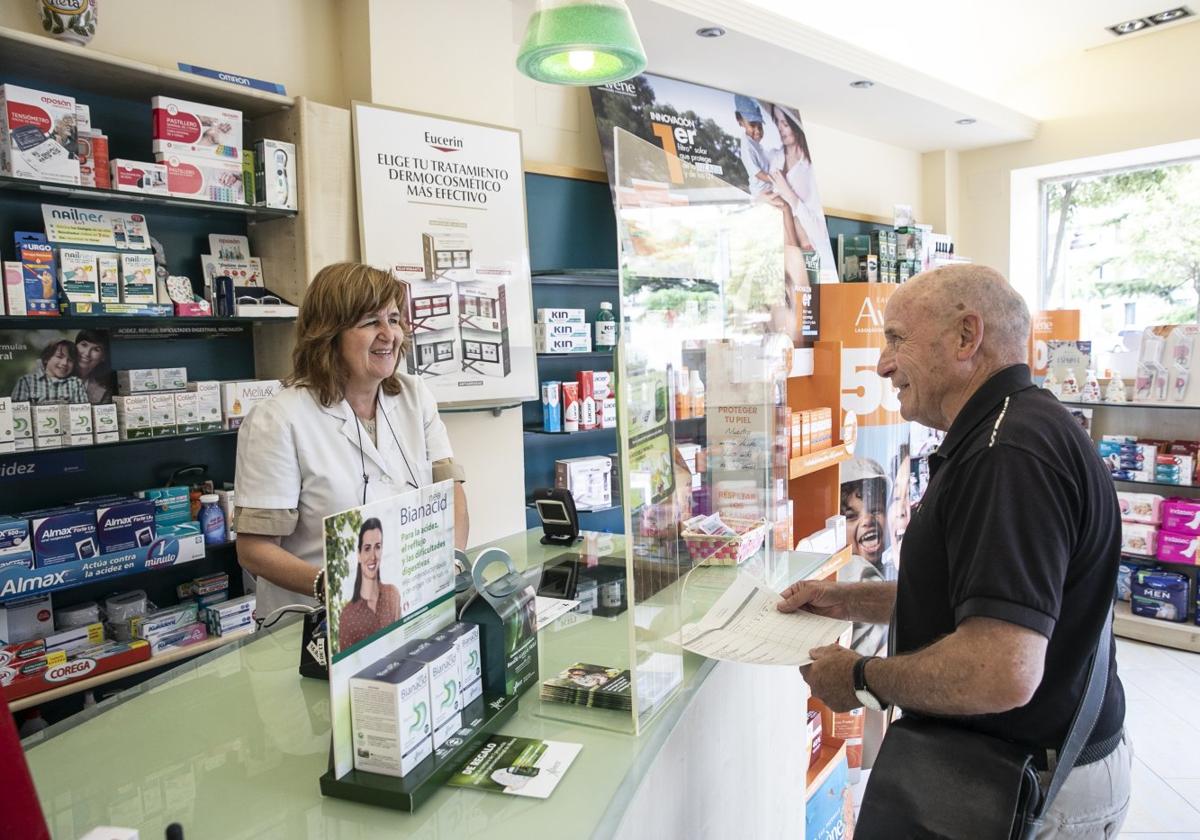 Mercedes Tutor atiende, este miércoles por la mañana, en su farmacia de la logroñesa calle Belchite a un cliente, Miguel Ángel Robredo.