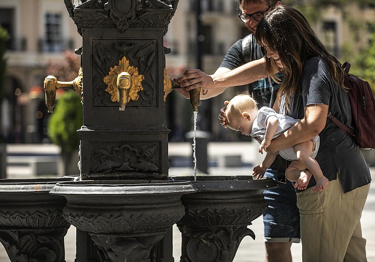 Una pareja refresca a su bebé en la fuente de la logroñesa plaza del Mercado, ayer.