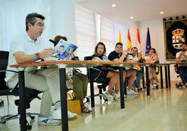 El edil de Vox Luis Emilio Mayoral muestra durante el pleno el programa electoral del PP, ante la atenta mirada del equipo de gobierno popular.