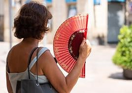 Mujer abanicándose a la sombra.