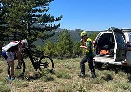 El ciclista inspecciona su bicicleta observado por un guardia civil.
