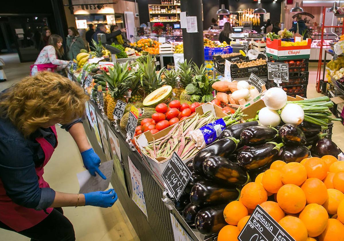 Dependientas colocan los precios de las frutas y verduras.