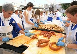 Las voluntarias de la peña preparan los bocadillos conel chorizo recién escaldado.