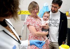 Noelia Jiménez y Rubén Carbonero sujetan a su hijo Martín mientras la enfermera prepara la dosis para inmunizarle frente a la bronquiolitis.