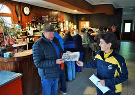 La cartera del Camero Viejo, Raquel Sáenz, entrega el periódico del día anterior al concejal de San Román, Pedro Royo, en la mañana de ayer en el bar Centro Social.