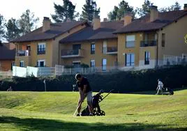 Un golfista juega en el campo de Sojuela con la urbanización Moncalvillo Green al fondo.