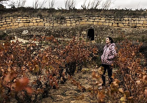 Rosana Lisa, entre cepas de tempranillo en Valhonta y con la choza al fondo. Abajo poda en el viñedo.