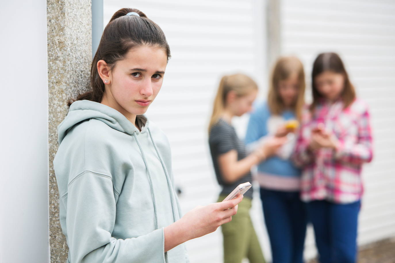 Una menor con un teléfono móvil cerca de sus amigas.