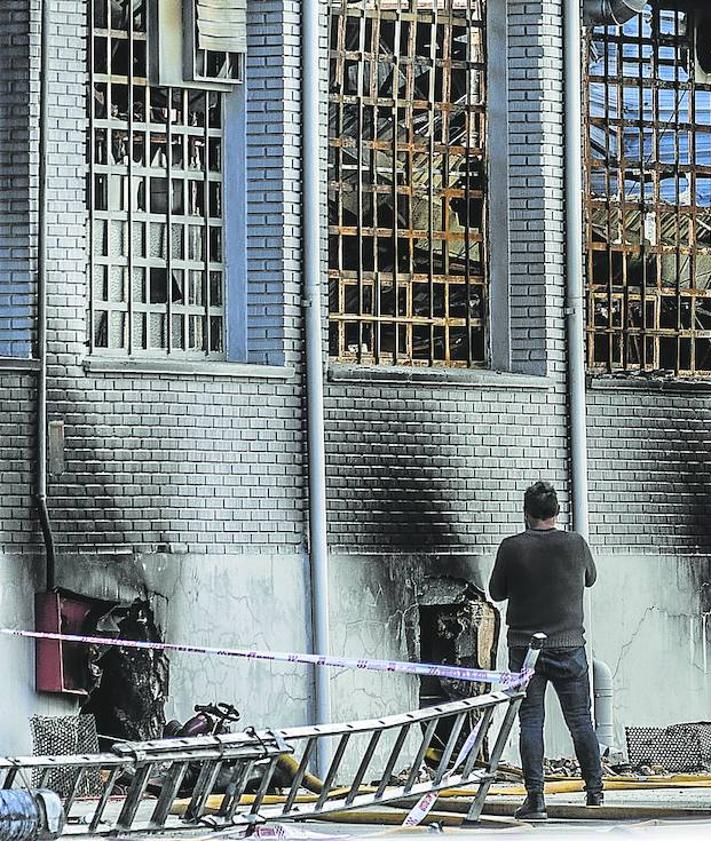 Imagen secundaria 2 - A la izquierda Antonio Guerrero, Mari Cruz Ruiz, Juan Pedro López, Juan Luis Ochoa, Rosa María Gil de Muro y Fernando Roldán observan la ruina que dejó el fuego en Calzados Fal. A la derecha después de que los bomberos abrieran huecos para atacar el fuego, el humo ya no salía este lunes de la nave.