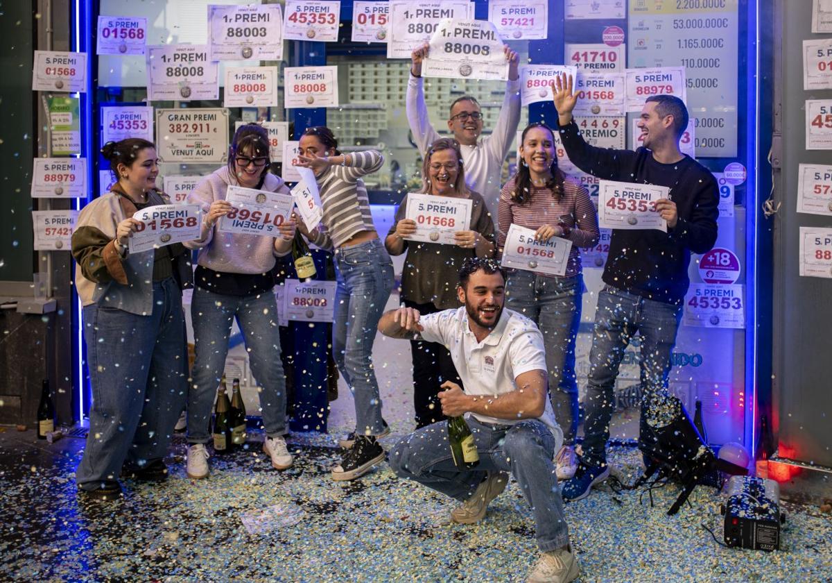 Agraciados con el Gordo del Sorteo Extraordinario de Lotería de Navidad celebran su suerte en la administración donde compraron sus décimos, en Barcelona.