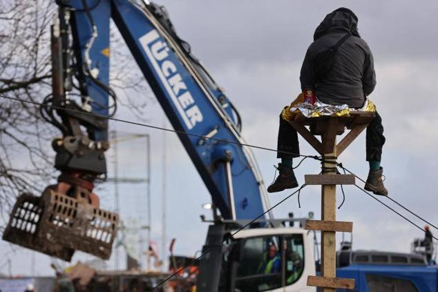 Un activista observa cómo una excavadora derriba una barricada instalada para obstaculizar el acceso de la Policía al pueblo.