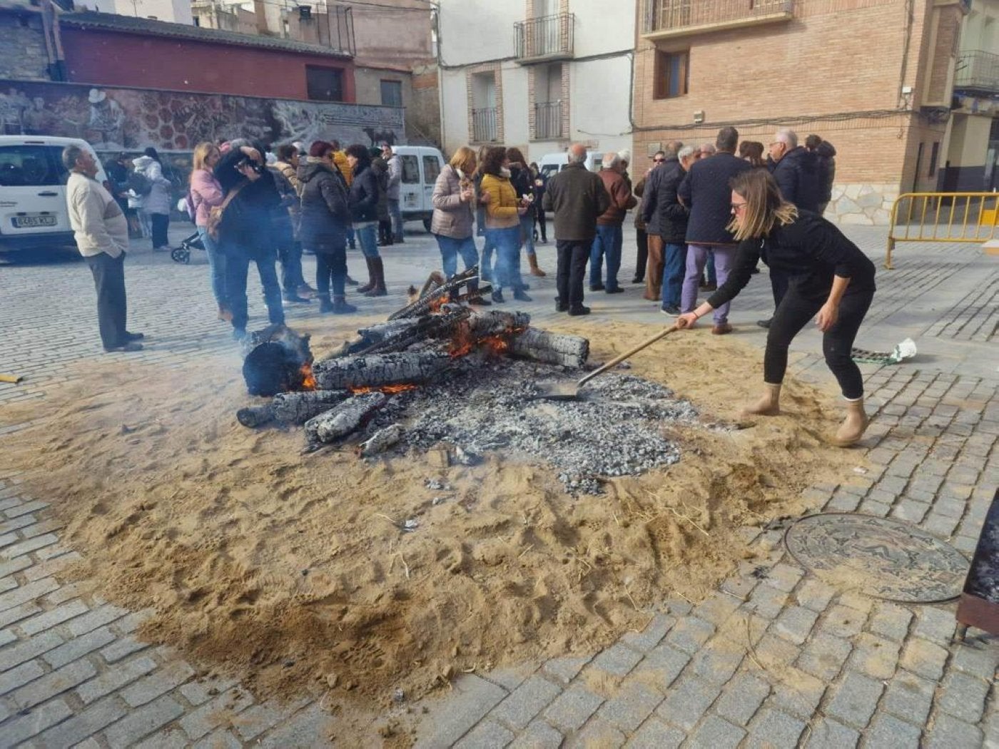 Una mujer extiende las brasas de la hoguera de ayer en Igea. 