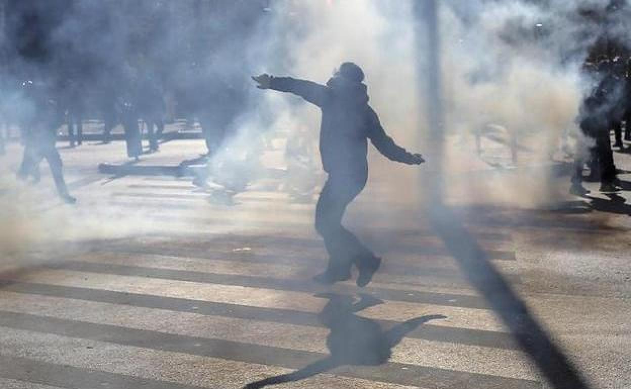 Un hombre arroja un objeto a la Policía antidisturbios durante los enfrentamientos registrados en Atenas frente a la sede del Parlamento.