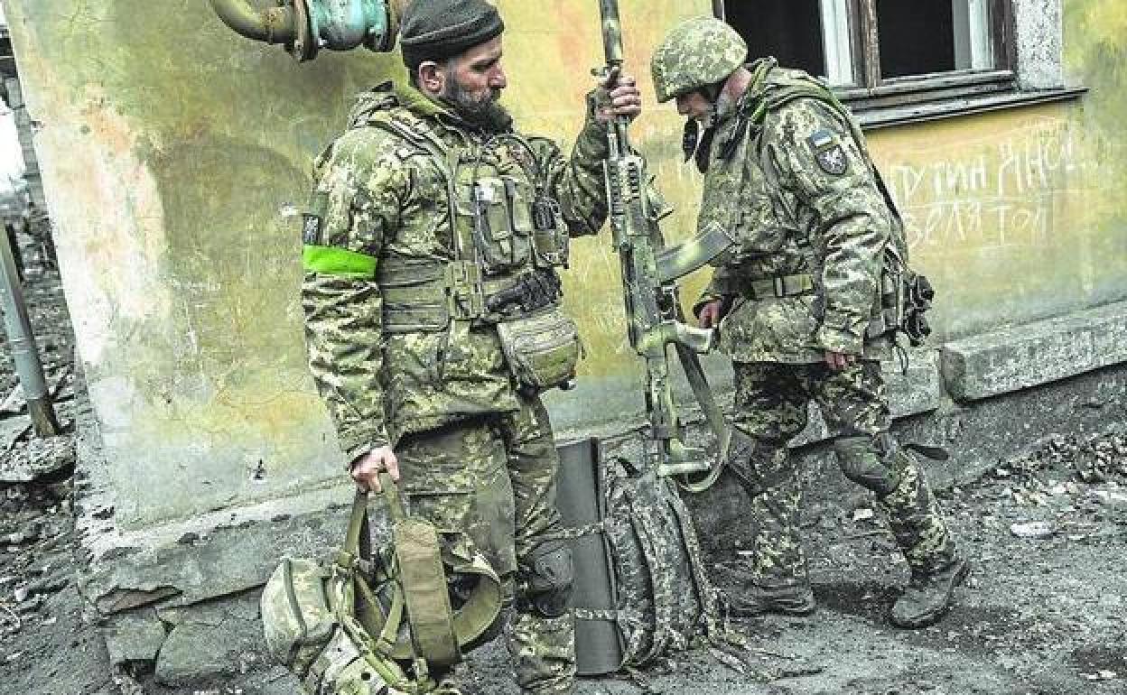 Dos soldados ucranianos desplegados en Bajmut recogen sus armas para dirigirse al frente.