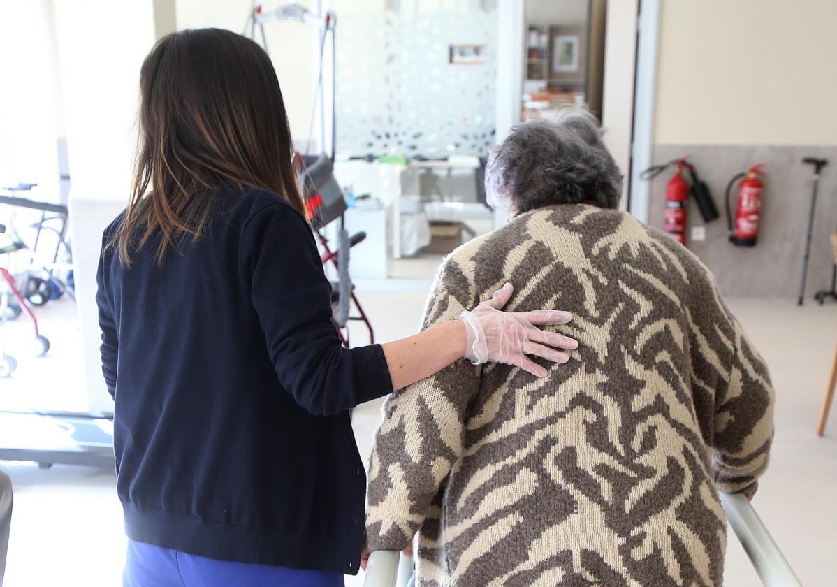 Una trabajadora ayuda a una personas mayor en una residencia.