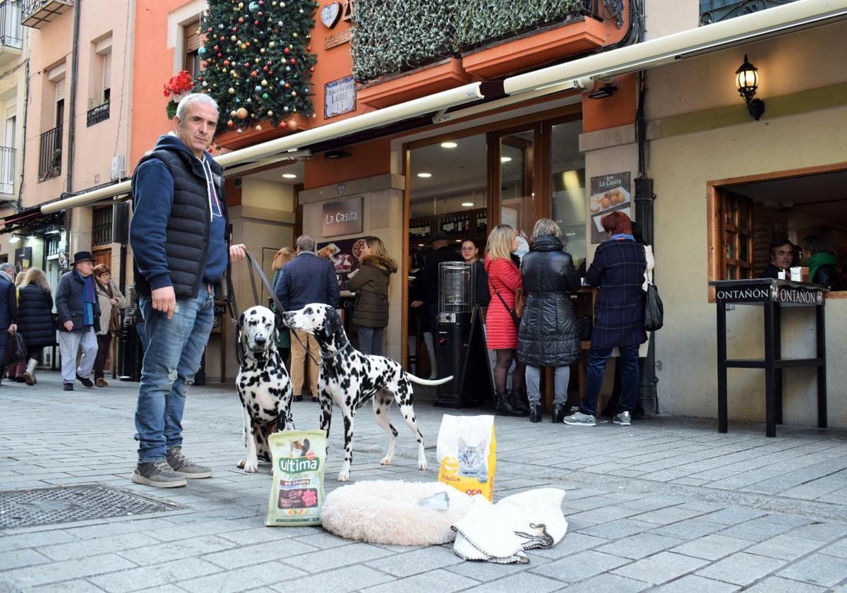 José Ruiz posa con los primeros donativos y sus perros en la puerta de su bar, La Casita, en La Laurel.