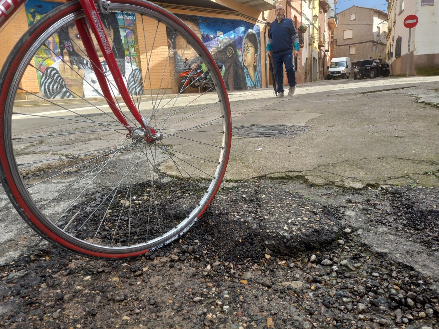 Una bicicleta encalla en un bache de la calle Las Parras de Villamediana de Iregua, una de las que se reurbanizarán.