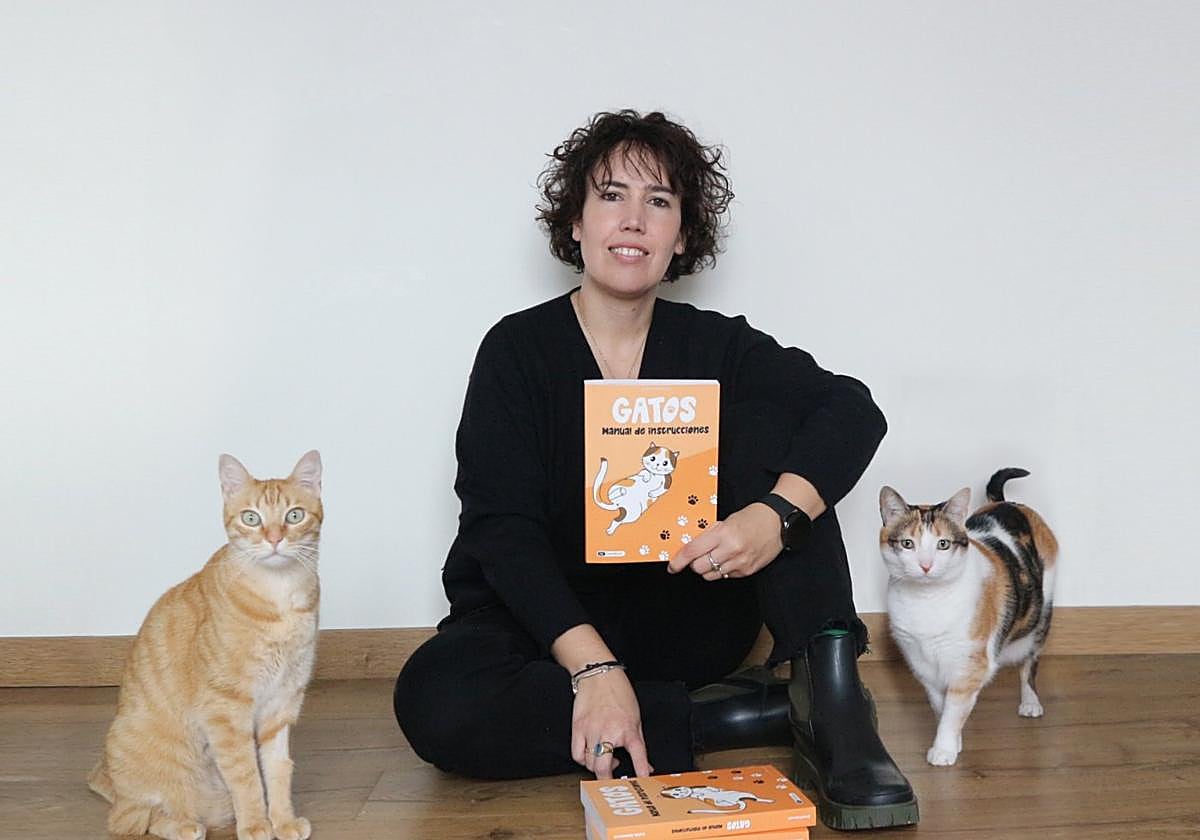 Celia Alesanco posa con su libro 'Gatos. Manual de instrucciones' junto a sus mascotas felinas Link y Zelda.