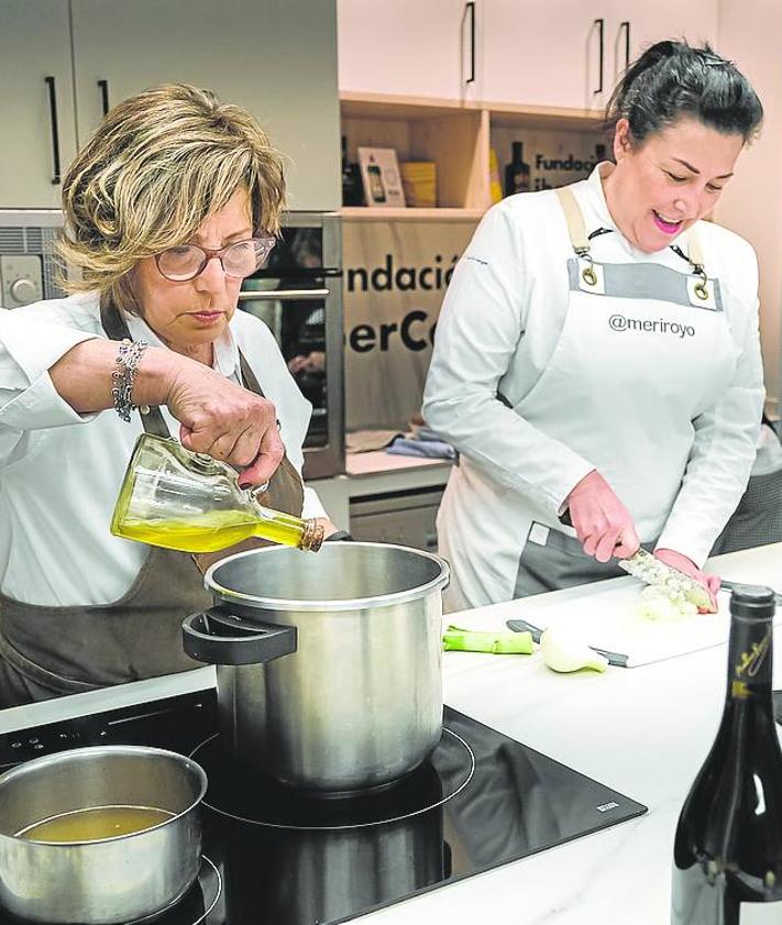 Imagen secundaria 2 - Arriba, dos alumnas pelan las patatas. Abajo a la izquierda, Pitu da sus explicaciones a los participantes en el curso. Abajo a la derecha Pitu y María Royo, durante la clase del pasado martes. 