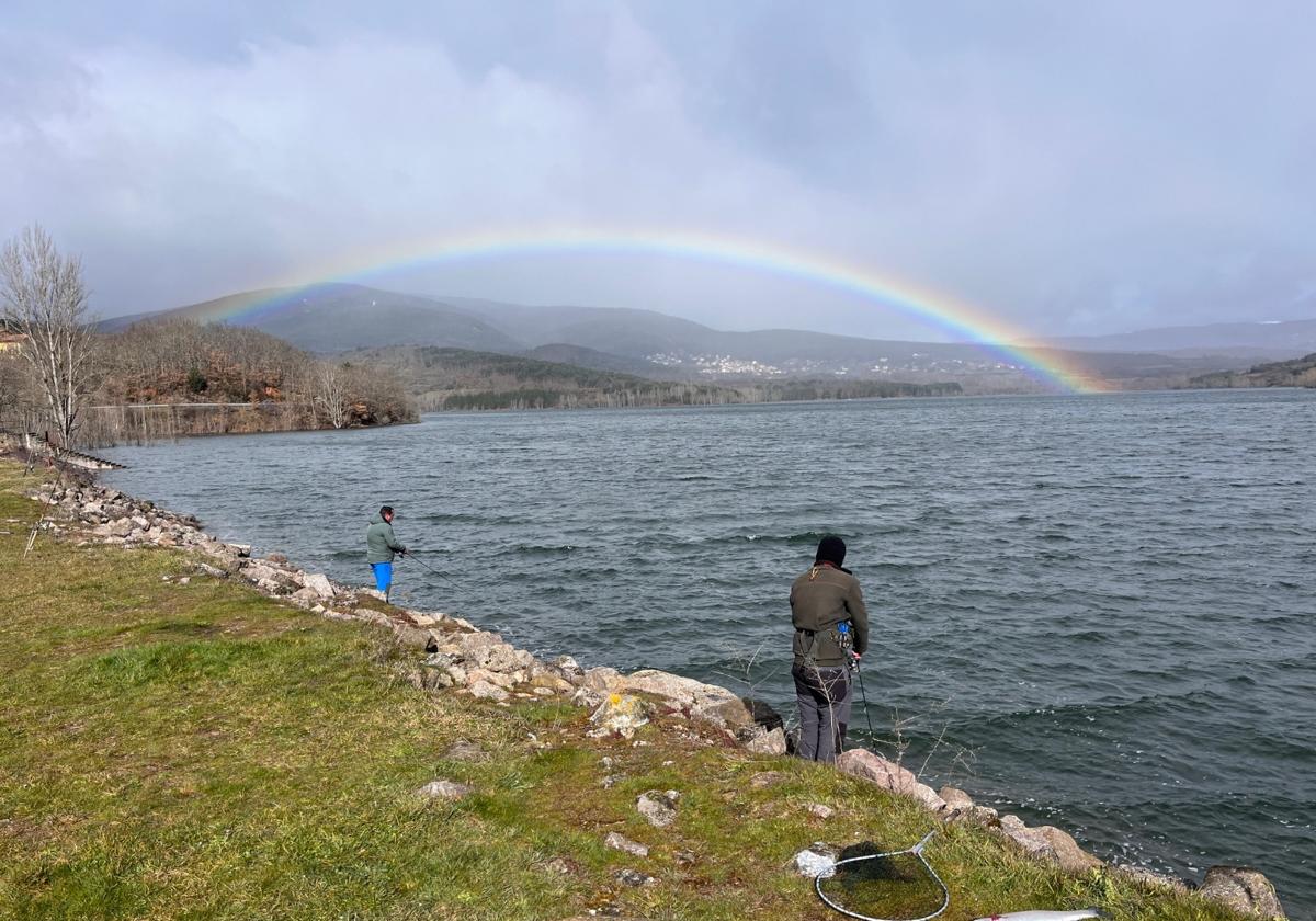 Varias personas echan sus cañas al agua del pantano González Lacasa.