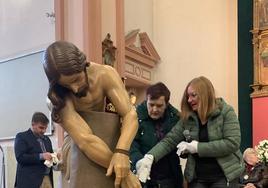 Una usuaria toca el Cristo con sus manos.
