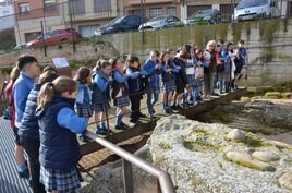 Grupo de escolares del colegio La Milagrosa, atendiendo a las explicaciones sobre los restos de las termas del yacimiento de La Clínica. Otra de las participantes, con un fragmento de cerámica.