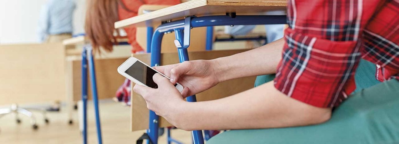 Un alumno manipula un teléfono inteligente en clase