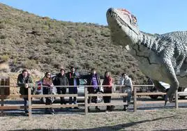 Organizadores del XXII EJIP junto a una réplica de un dinosaurio en al camino de acceso al yacimiento de Los Cayos de Cornago.