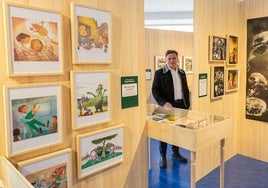 El ilustrador Manuel Romero posa junto a sus trabajos en la exposición de la Biblioteca Rafael Azcona.