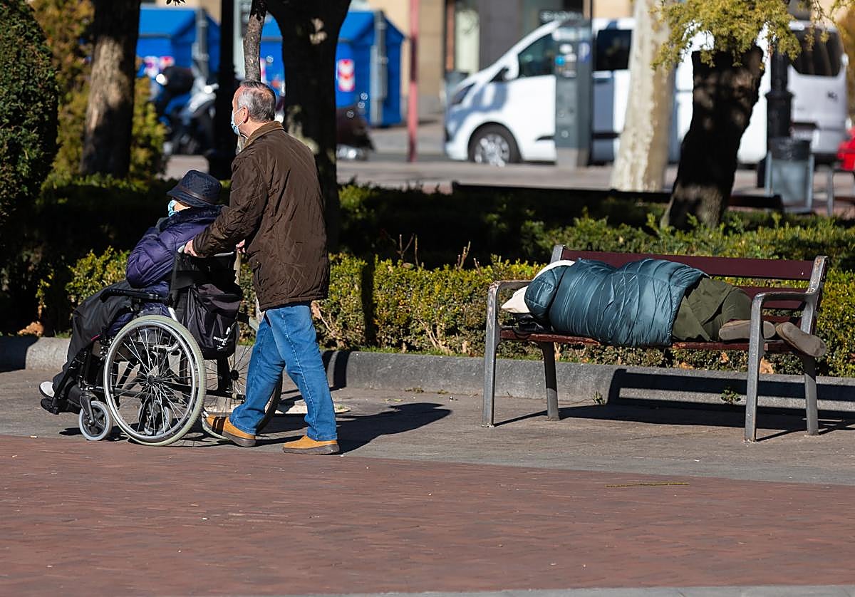 Una persona sin techo duerme en uno de los bancos del Espolón.