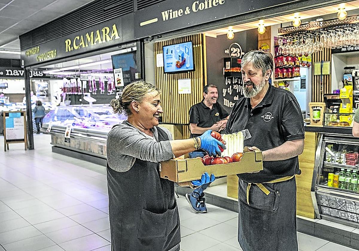 Arancha, de frutas Carlos Aragón, lleva sus productos a José Macaya, del bar 'El 23', del propio mercado del Corregidor.