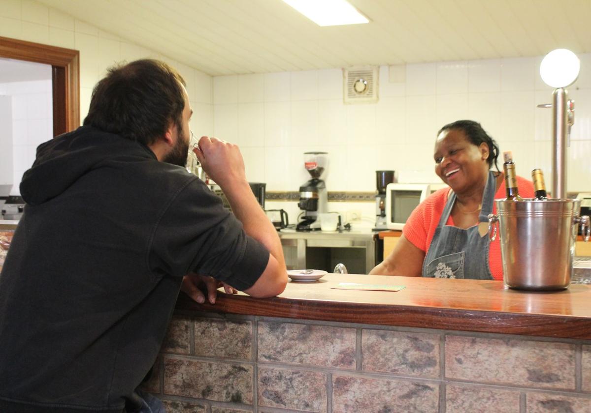 Nora Alicia charla desde detrás de la barra con un cliente habitual mientras él toma un café.